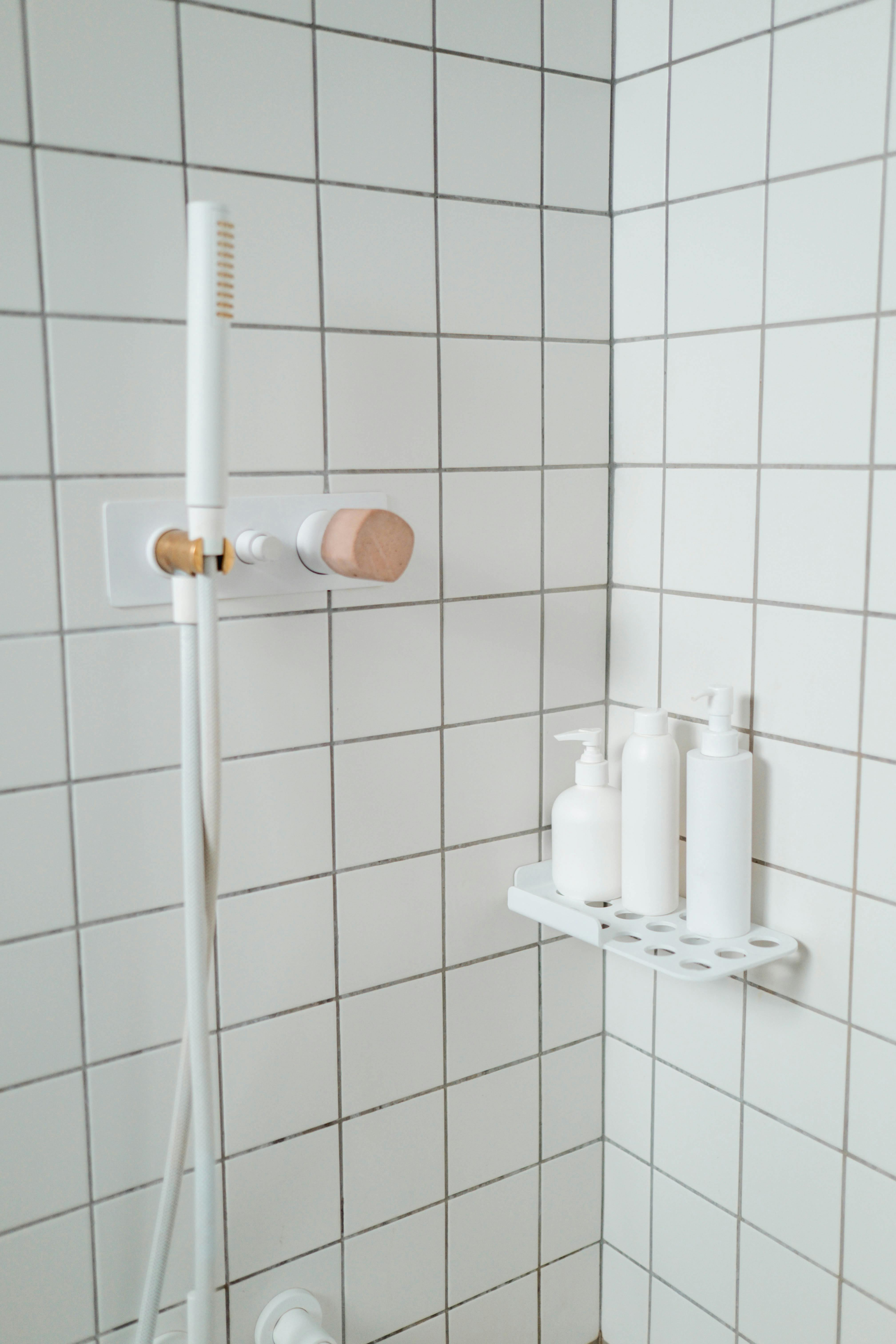 white minimalist bath products in white tiled shower